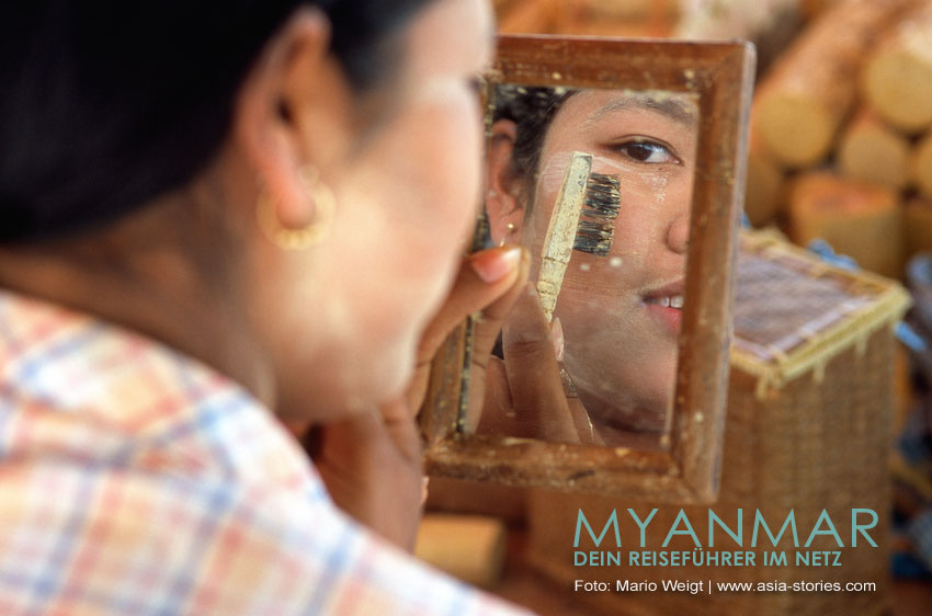 Die Thanaka-Paste wird mit einer kleinen Bürste im Gesicht aufgetragen und verteilt.