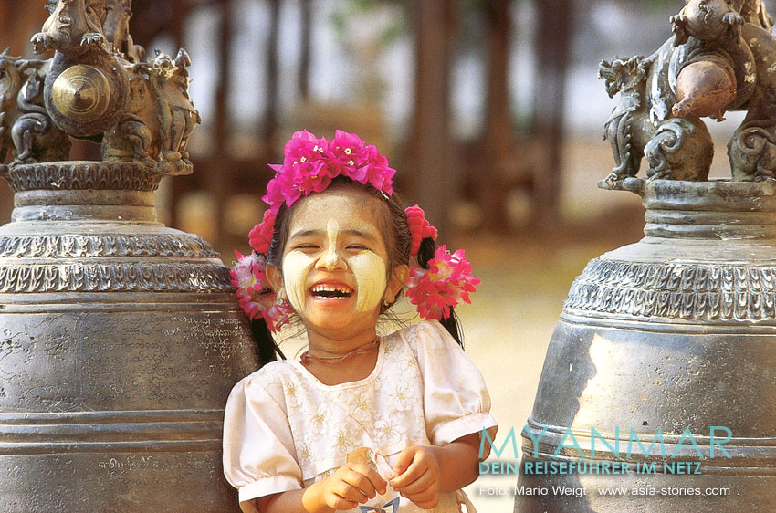 Lachendes Mädchen mit Thanaka-Paste im Gesicht.