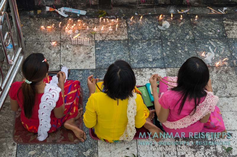 Frauen mit Gebetsketten beim Beten vor dem Goldenen Felsen Kyaikhtiyo in Myanmar