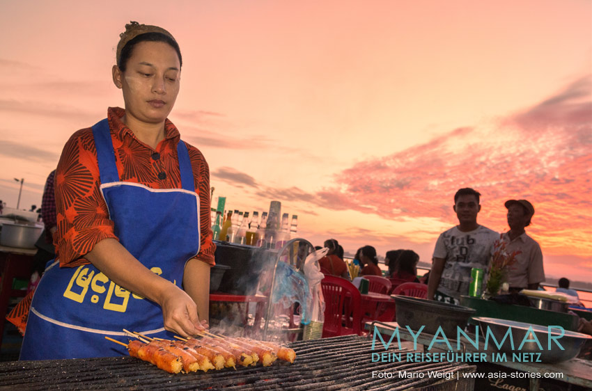 Eine Frau verkauft Grillspieße auf dem Nachmarkt in Mawlamyaing.