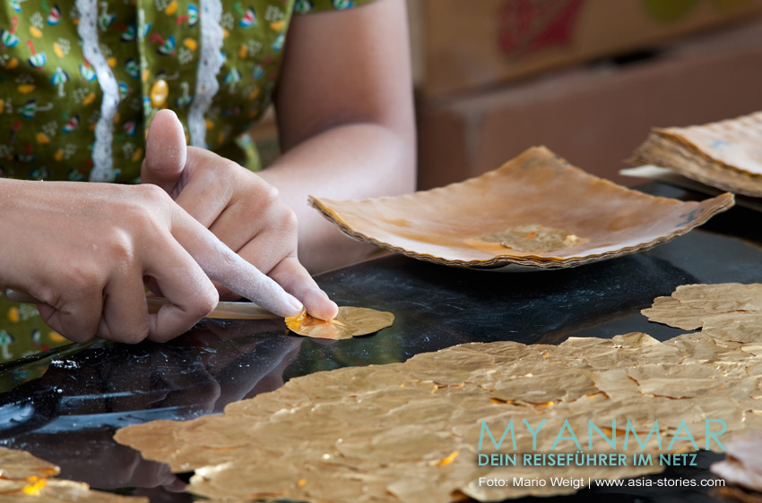 Eine Frau setzt Goldplättchen in der Blattgoldmanufaktur King Galon in Mandalay zusammen.