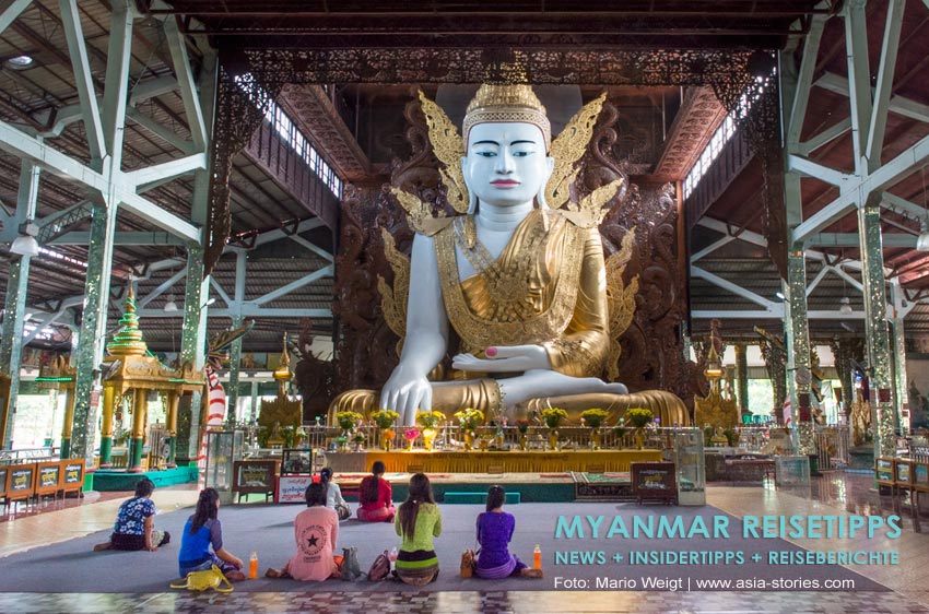 Betende Pilger sitzen vor dem vergoldeten Buddha in der Pagode Nga Htat Gyi in Yangon.