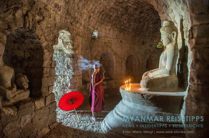 Betender Mönch im Kerzenschein vor einer der vier Buddha-Statuen im Laymyethna-Tempel