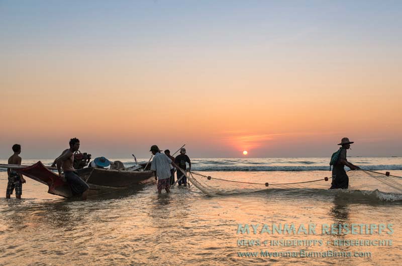 Fischer packen am Ngwe Saung Beach in Myanmar ihr Netz für den nächsten Morgen zusammen.