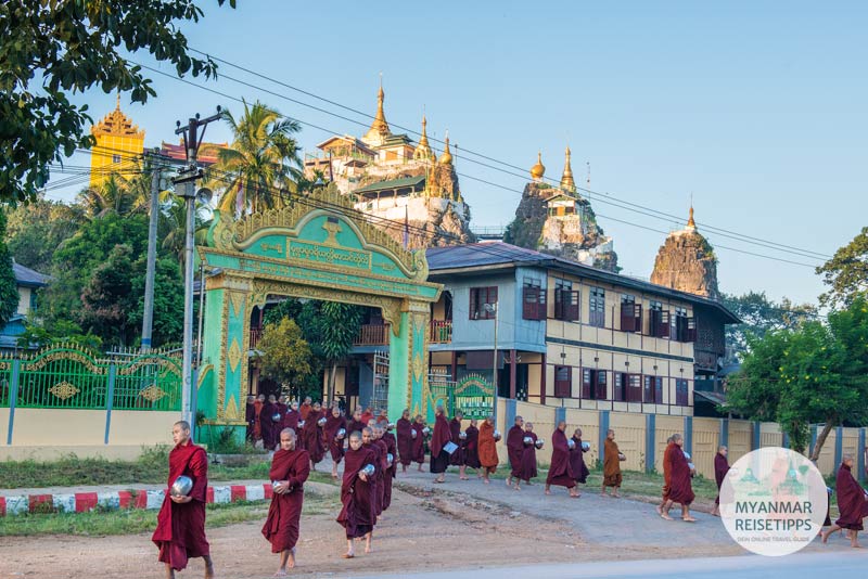 Mönche beim Almosengang in Loikaw. Im Hintergrund ist die Pagode Taung Kwe zu sehen.