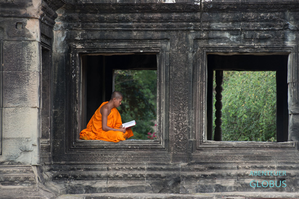 Kambodscha, Angkor: Ein Mönch sitzt in der in der ehemaligen Bibliothek in der Tempelanlage Angkor Wat und liest ein Buch .