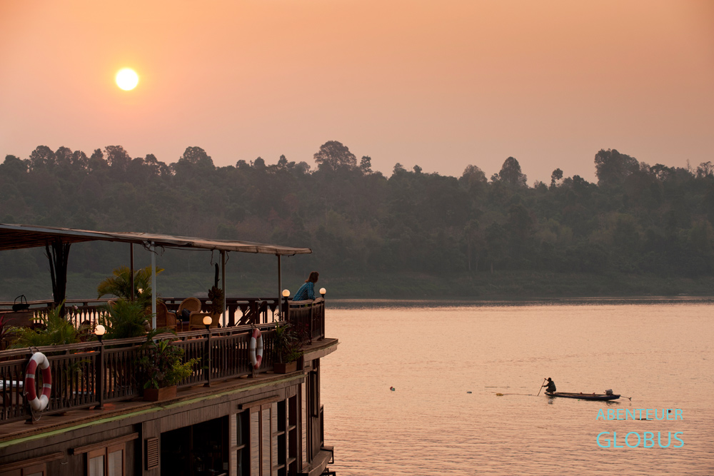 Mekong, Laos, bei Champasak, Sonnenaufgang an der Lebensader Südostasiens. Reisende sind mit dem Kabinenschiff Mekong Sun stromabwärts unterwegs.