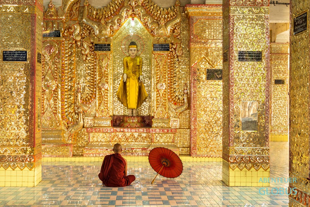 Myanmar, Mandalay, Mandalay Hill, Ein tief in Meditation versunkener Mönch in Mandalay. Sein roter Bambusschirm dient ihm als Regen- aber vor allem als Sonnenschutz.
