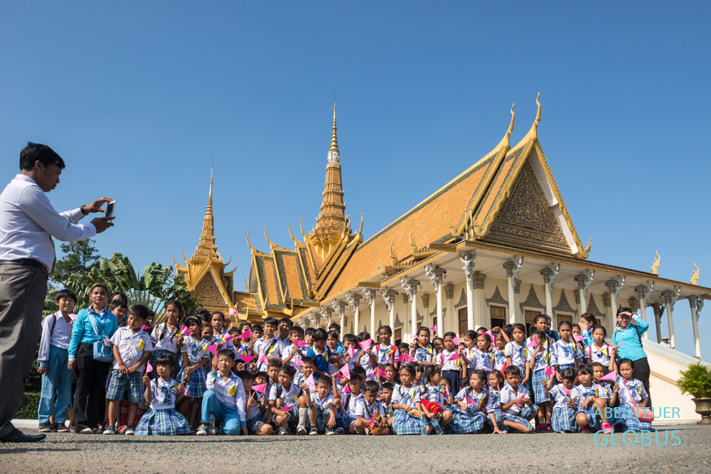 Ein Lehrer fotografiert eine Gruppe Schüler vor dem Königspalast.