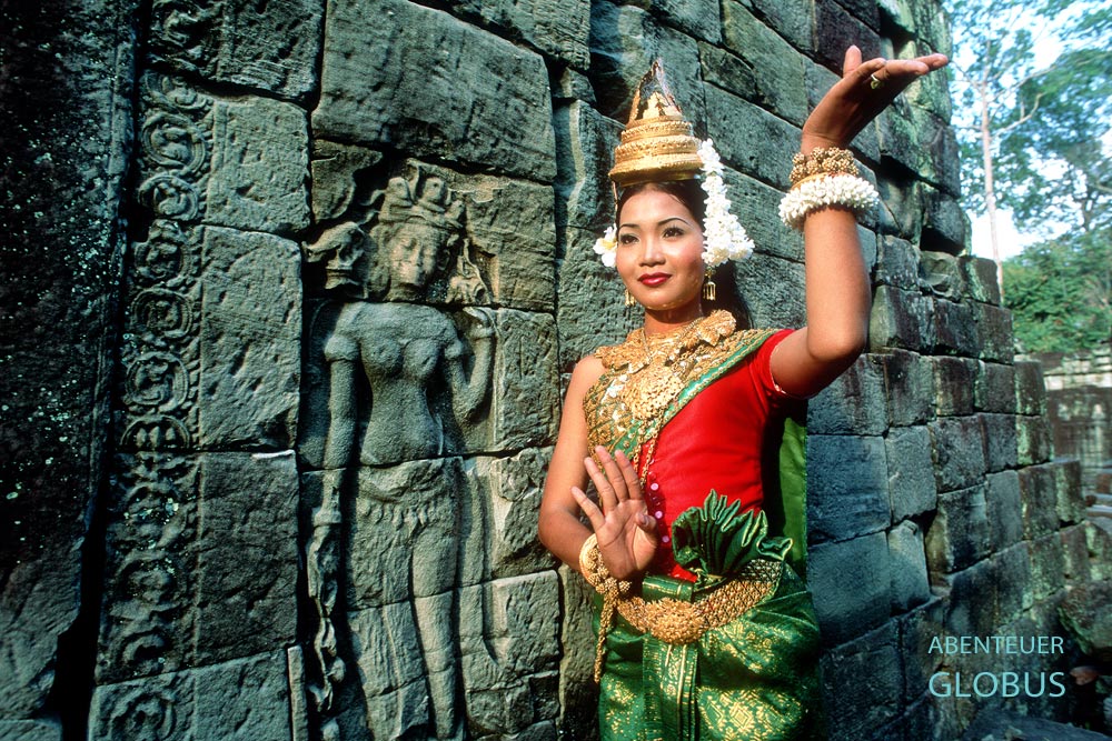 Apsara-Tänzerin posiert neben einer Stein-Apsara im Tempel Preah Khan der Tempelanlage Angkor, Kambodscha.
