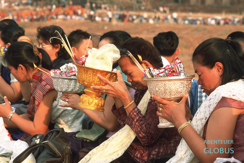 Gläubige beten mit Opfergaben vor der Spendenzeremonie Tak Baat zum Vollmondfest am Tempelkomplex Wat Phou in Champasak in Süd-Laos.