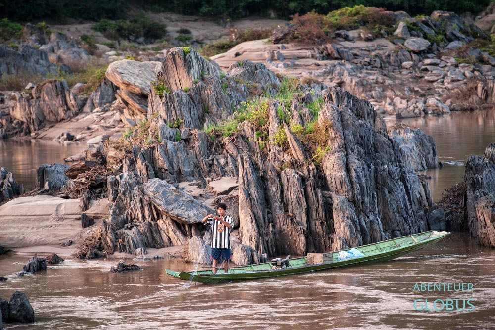 Fischer auf dem Mekong. Zur Trockenzeit ragen immer mehr schroffe Felsen und Sandbänke aus dem Wasser.