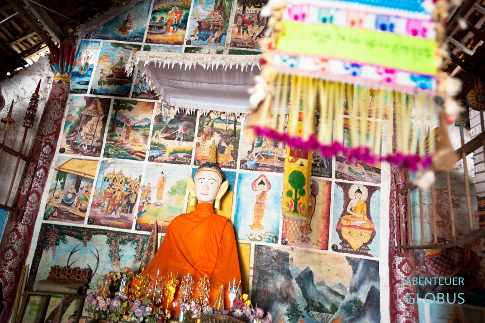 Die Buddha-Statue im Dorfkloster von Vieng Keo hat eine neue orangefarbene Robe zum Elefantenfest erhalten.