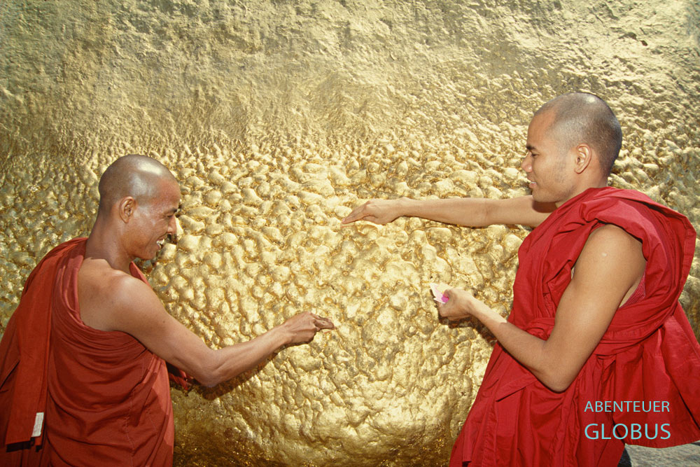 Mönche bringen Goldplättchen an den Goldenen Felsen Kyaiktiyo nahe dem Ort Kyaikto in Myanmar an.