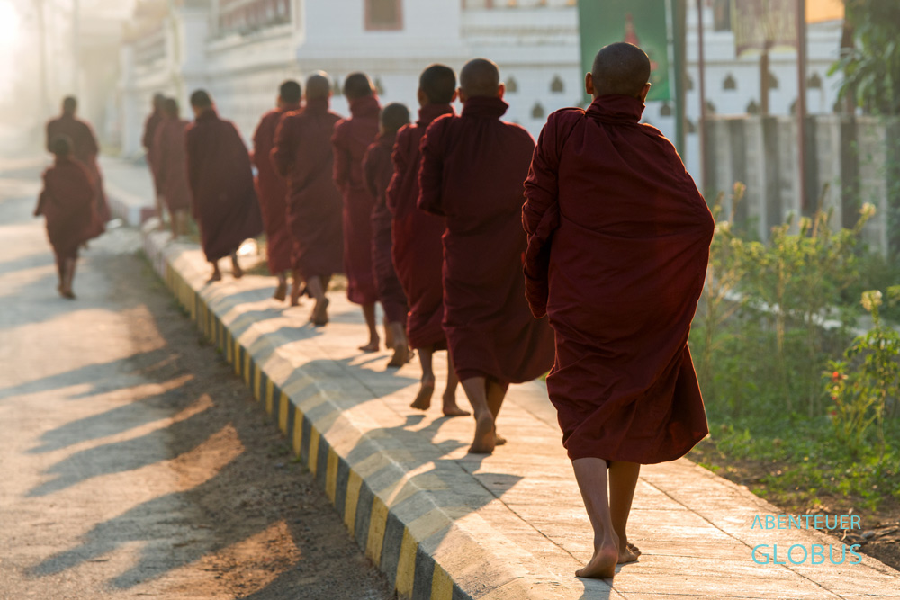 Barfuß schreiten die Mönche und Novizen in einer Prozession durch Nyaungshwe am Inle-See in Myanmar.