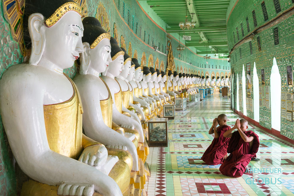 Auf dem Sagaing Hill beten junge Mönche vor Gold-Buddhas in der Umin-Thounze-Pagode nahe Mandalay in Myanmar.