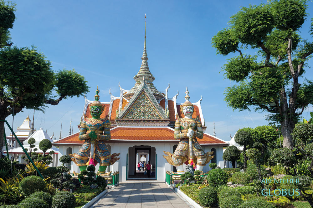 Zwei Tempelwächter stehen im Garten vom Wat Arun, Tempel der Morgenröte. Dieser Tempel befindet sich in Thailands Hauptstadt Bangkok.