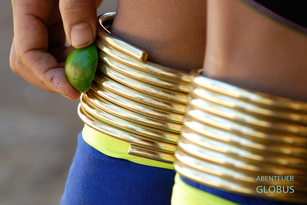 Hand einer Padaung-Frau reinigt Messingspiralen an den Beinen mit Limette.