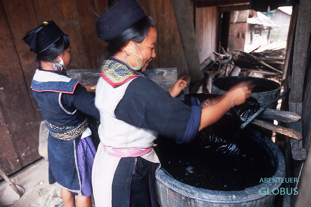 Frauen der Schwarzen Hmong färben ihre Baumwollkleider in Tonnen mit indigoblauer Farbe.