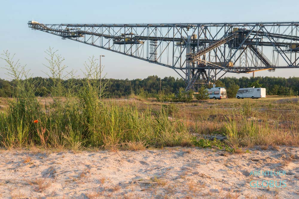 Wohnmobile am Bergheider See in Lichterfeld-Schacksdorf. Die Camper stehen mit Sicht auf die Abraumbrücke F60, außerhalb des Besucherbergwerks.