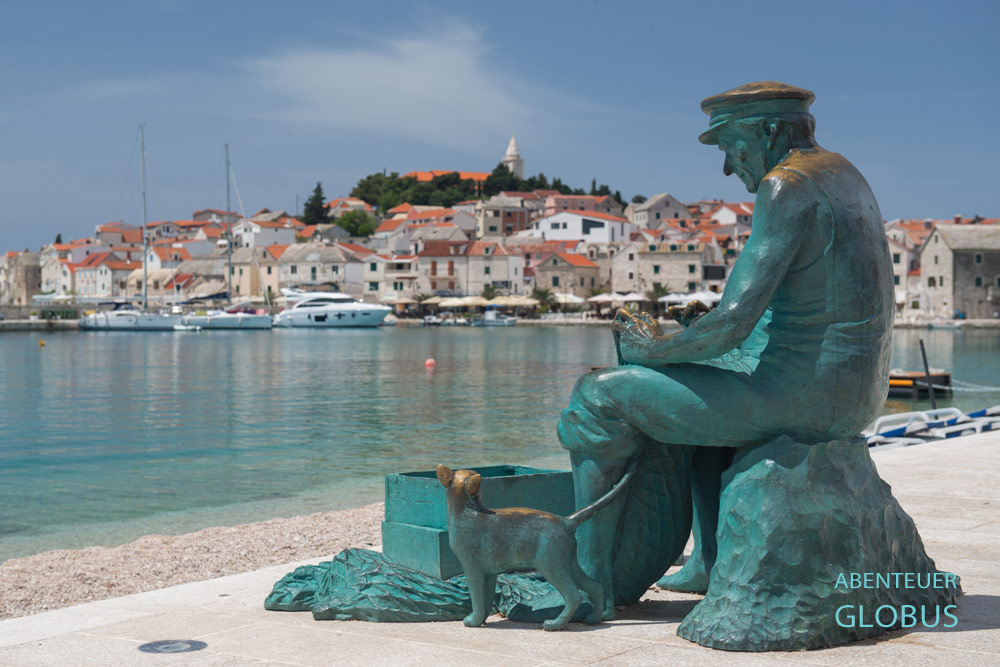 Statue Fischer mit Katze am Luka-Strand und Altstadt Primosten in Kroatien