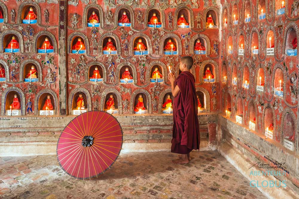 Betender Mönch vor Buddha-Statuen: Fotoserie Der Rote Schirm aus Südostasien, Fotograf Mario Weigt