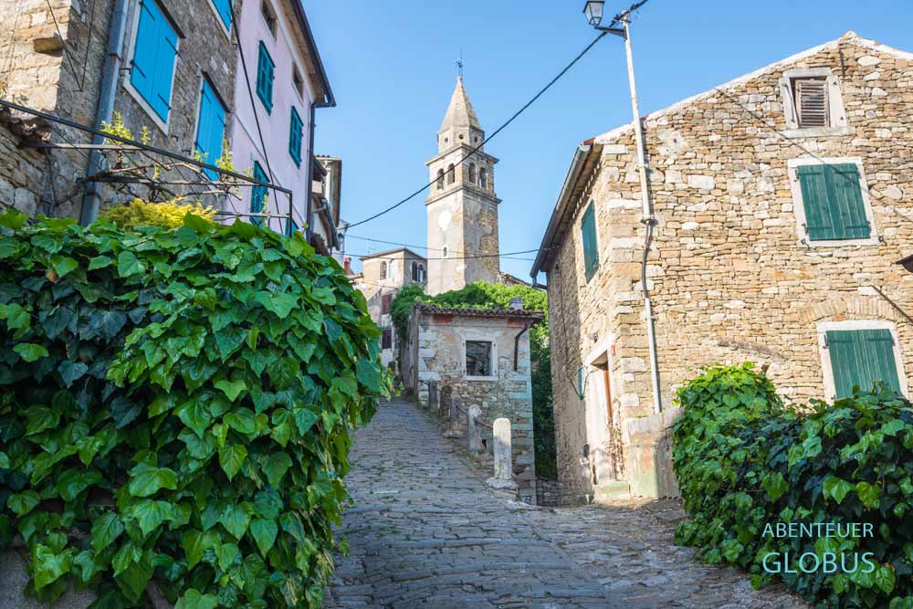 Steinhäuser an gepflasterten Gassen und Kirche des Heiligen Johannes in der Altstadt Motovun in Istrien in Kroatien