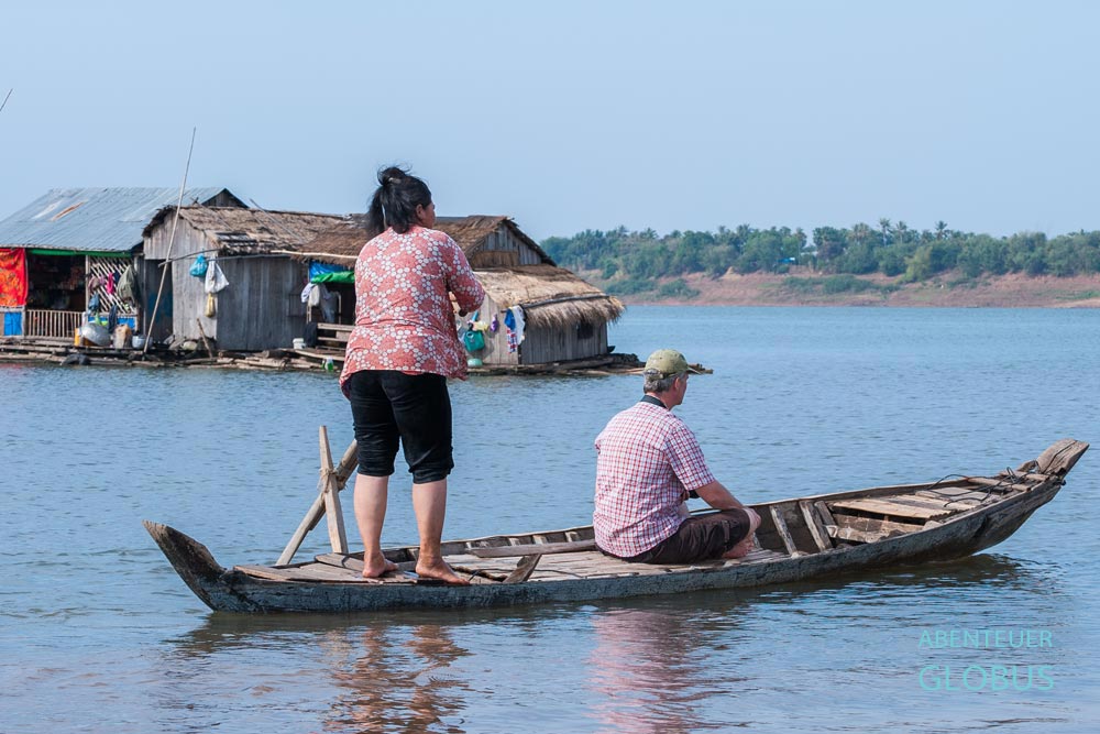 Vietnamesische Frau mit Tourist rudert ein Holzboot in einem schwimmenden Dorf bei der Insel Koh Trong in Kambodscha.