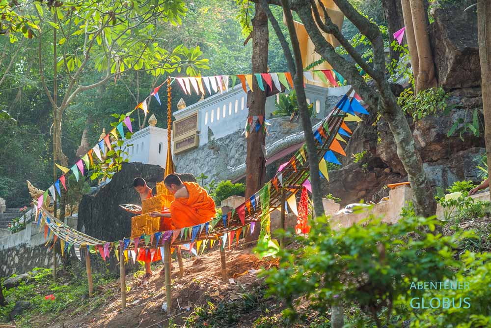 Festivals und Highlights in Luang Prabang in Laos: Mönche bauen ein Bambusboot für das Lichterfest Bun Ok Phansa.