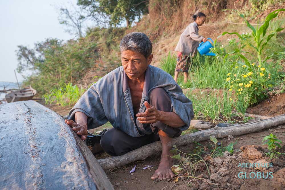 Mann repariert ein Boot am Mekong auf der Insel Don Khong, Laos.