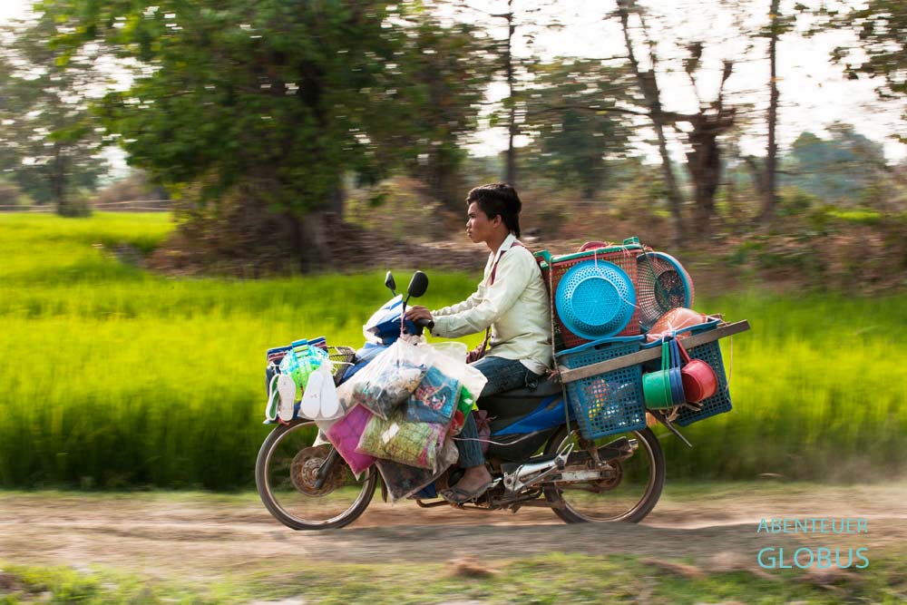 Händler fährt mit einem mit Haushaltswaren beladenen Roller auf der Insel Don Som, Laos.