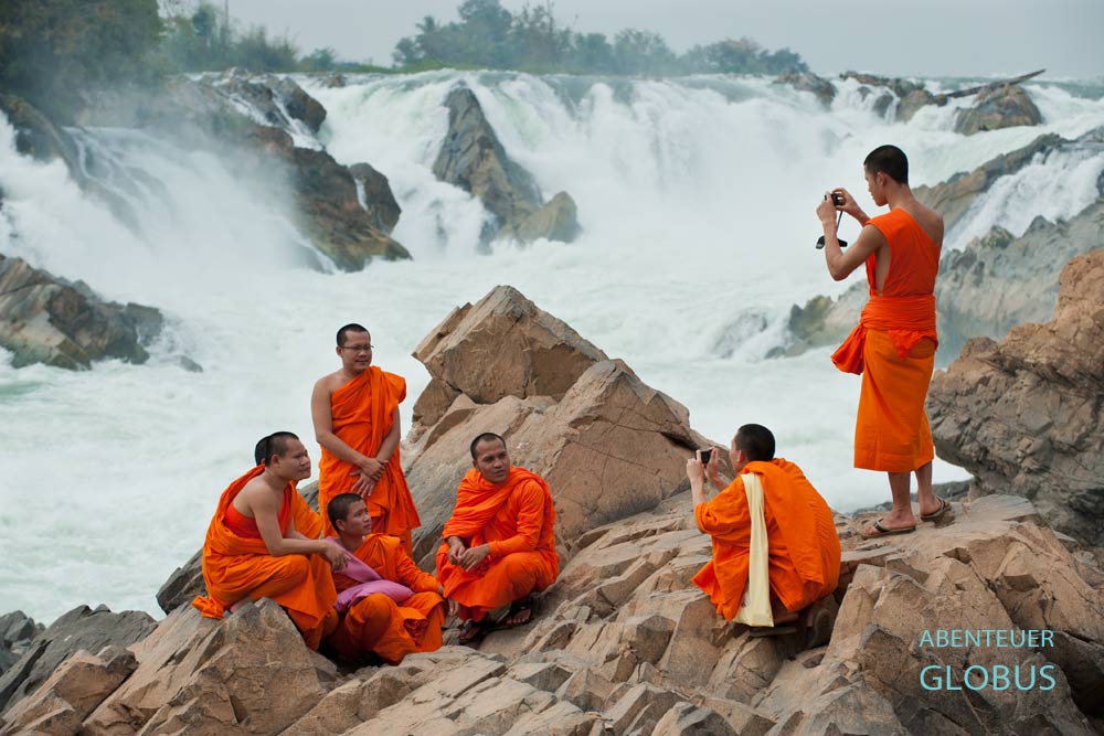 Buddhistische Mönche fotografieren sich an den Khon Phapheng-Wasserfällen im Mekong-Delta Si Phan Don, Laos.
