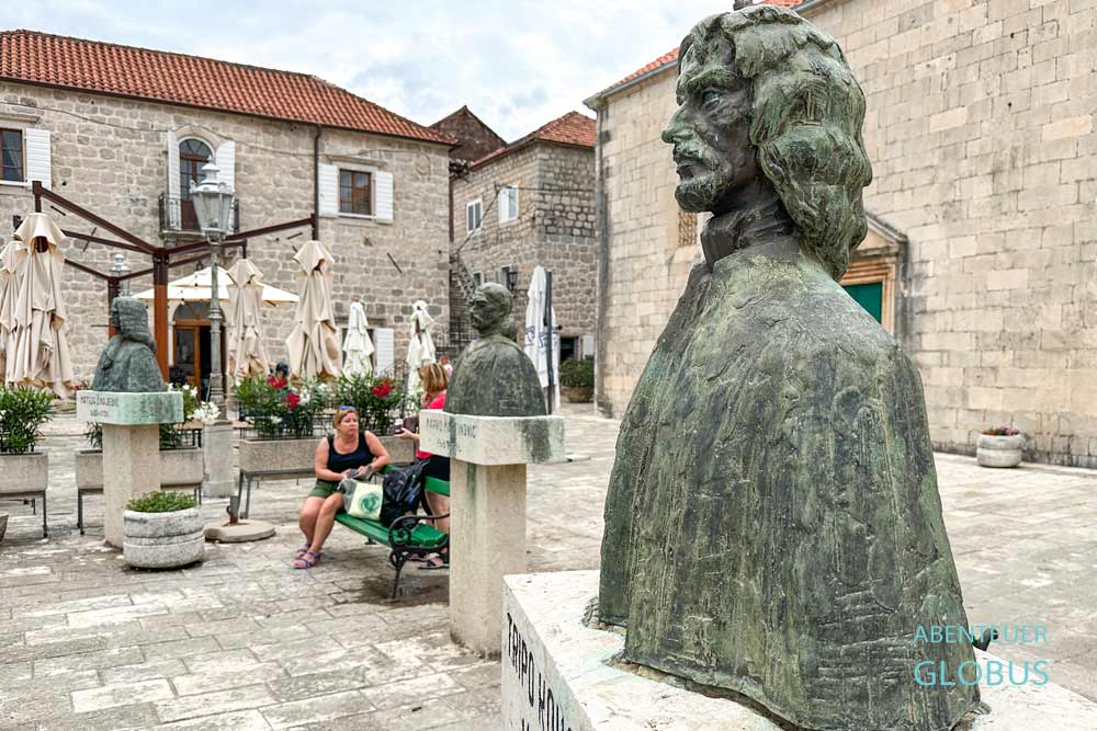 Platz mit Büsten berühmter Personlichkeiten an der Kirche des Heiligen Nikolaus in Perast
