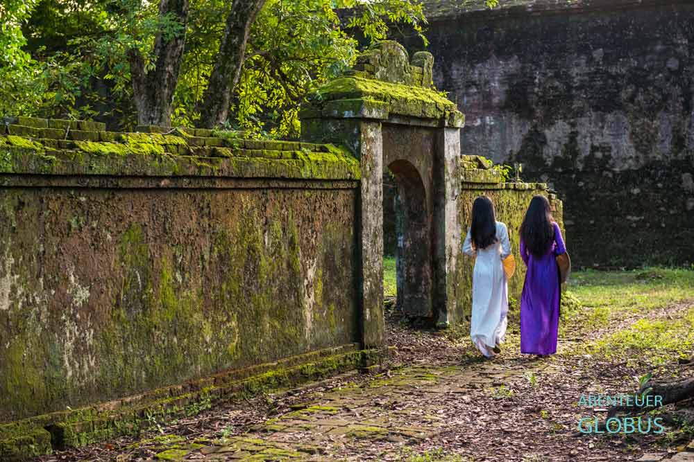 Frauen mit dem traditionellen Ao Dai spazieren Kaisergrab Tu Duc.