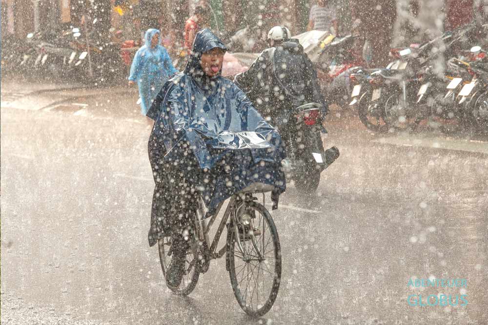 Regenzeit in Thailand: Ein Mann fährt Fahhrad bei heftigem Regen.