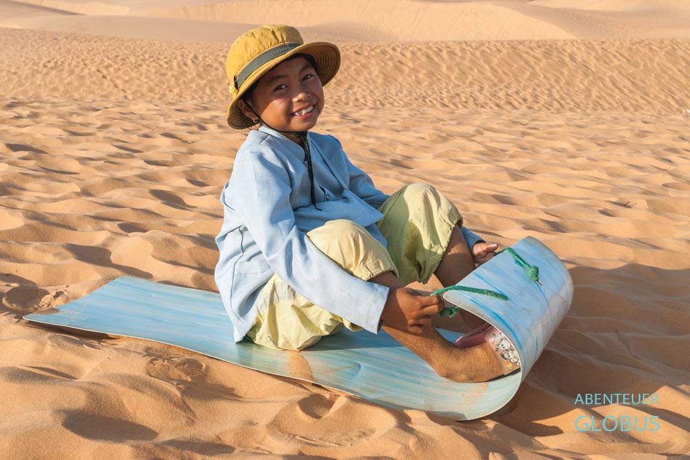 Sehenswürdigkeit in Mui Ne: rote Sanddünen, Kind beim Rutschen mit einer Plastikplane