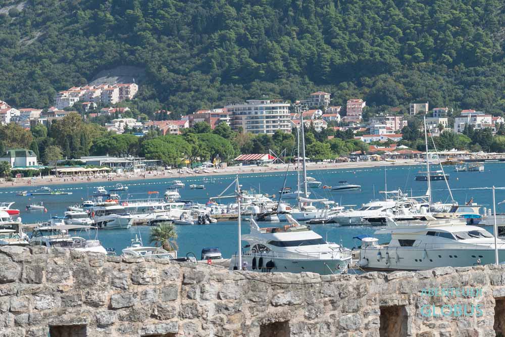 Blick von der Stadtmauer in Budva: Hafen und Strand Slovenska Plaza