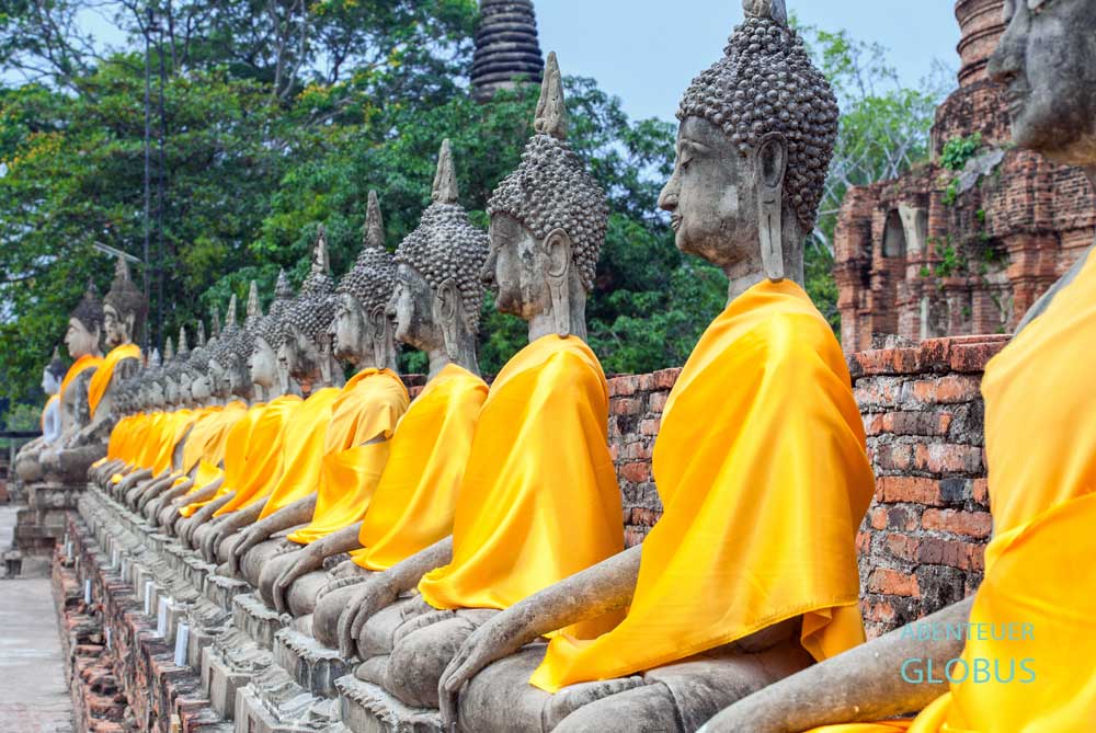 Buddhareihe mit orangfarbenen Gewändern in Ayutthaya