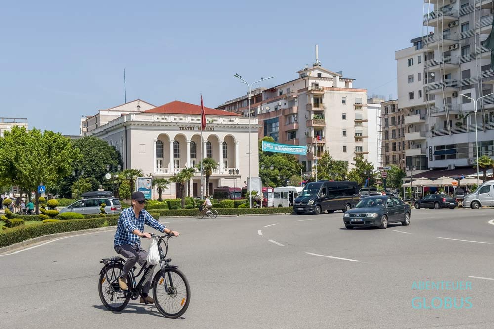 Kreisverkehr am Platz der Demokratie (Sheshi Demokracia) mit dem Theater Migjeni und Fahrradfahrer