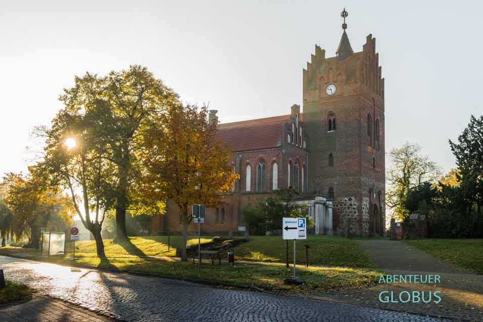 Am Morgen wirkt die Ortschaft Linum noch verlassen. Die Kirche von Linum im Gegenlicht. 