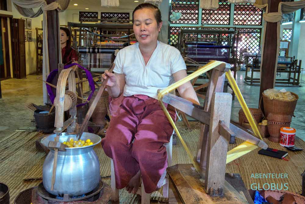 Eine Mitarbeiterin haspelt den Seidenfaden von den Kokons auf eine Spule.