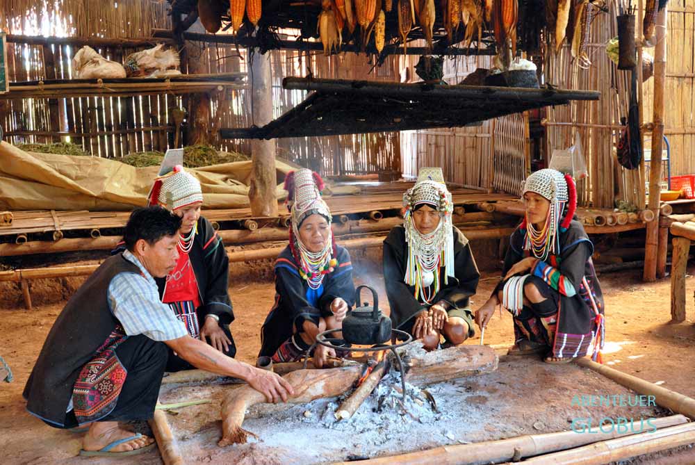Bergvolk der Akha in traditioneller Tracht an einer Feuerstelle nahe Chiang Mai beim Trekking
