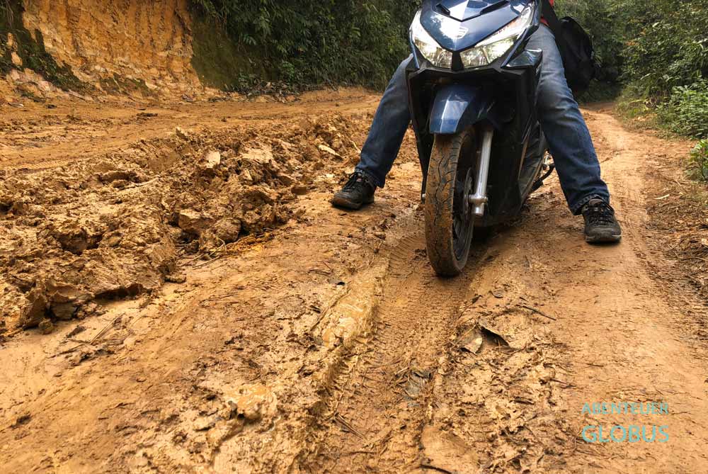 Fahrer mit einem Roller auf einer Schlammpiste in Thailand