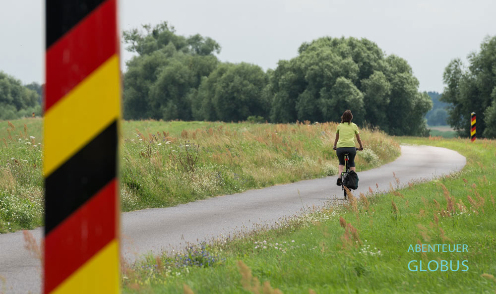 Radfahrerin zwischen zwei Grenzpfosten am Oder-Neiße-Radweg zwischen Lunow-Stolzenhagen und der Ortschaft Lunow im Nationalpark Unteres Odertal