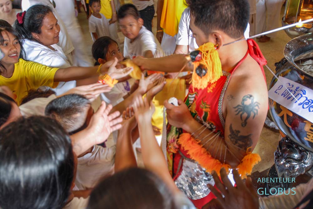 Dieser Ma Song verteilt im Kathu Schrein gesegnete Fähnchen mit buddhistischen Motiven.