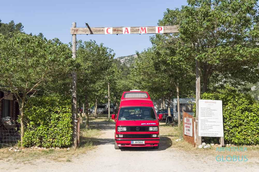 Eingang des Autocamps Heaven in Nature in Stolac mit rotem VW T3 Atlantic.