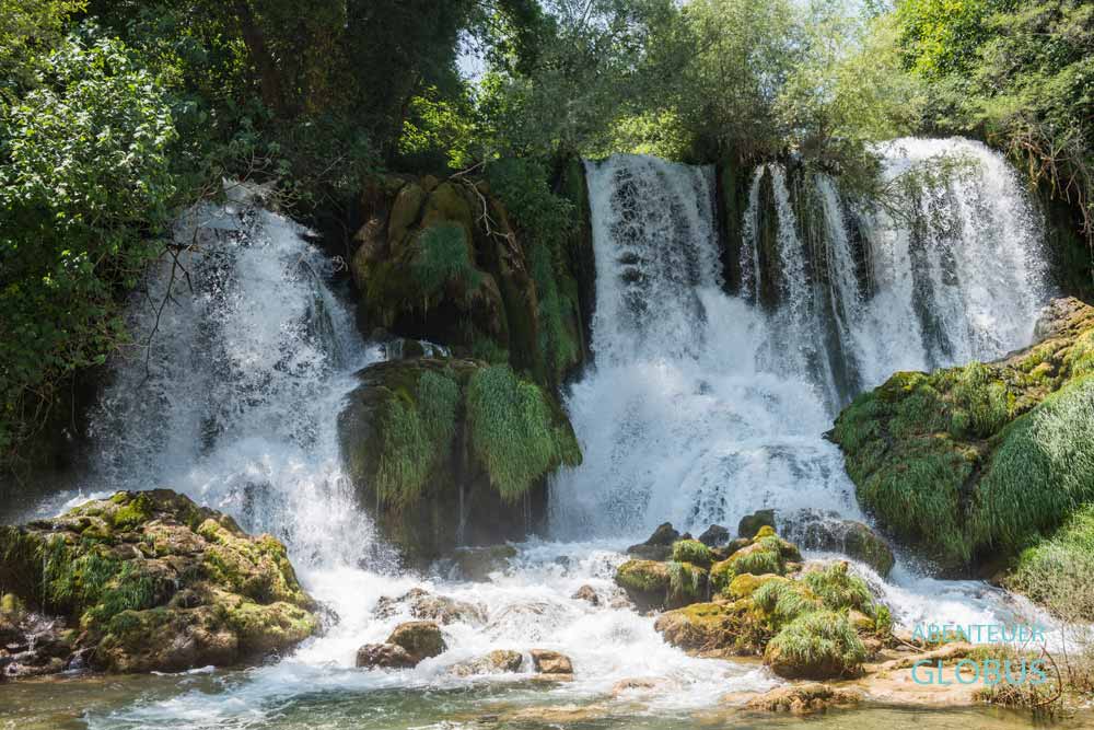Am Wasserfall Kravica fließt der Fluss Trebizat über bewachsene Tuffsteinkaskaden.