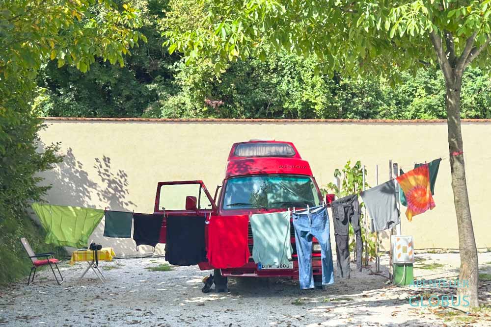 Campervan auf einem Stellplatz vom Campingplatz Camping Sarajevo, davor hängt Wäsche.
