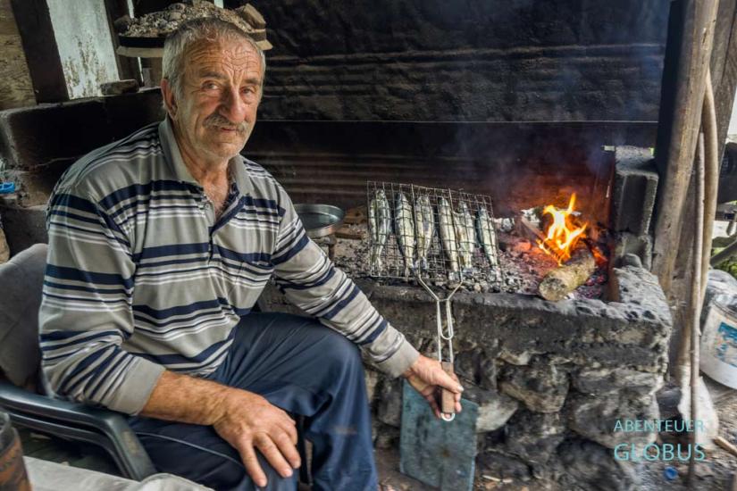 Der Besitzer Pele grillt Forellen über einer offenen Feuerstelle im Restaurant Bascica.