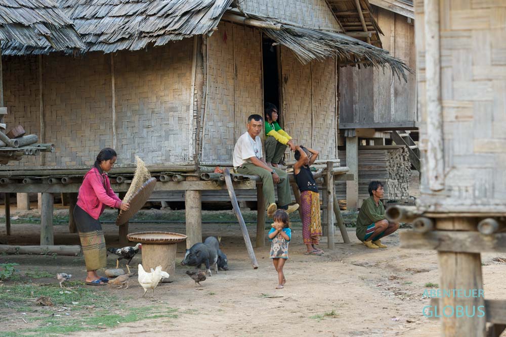 Eine Familie sitzt vor ihrer Bambusmattenhütte im Dorf Ban Sop Jam.